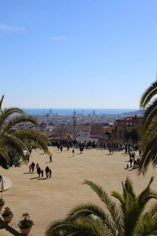 Widok z głównego tarasu Park Güell w Barcelonie na panoramę miasta i morze między palmami