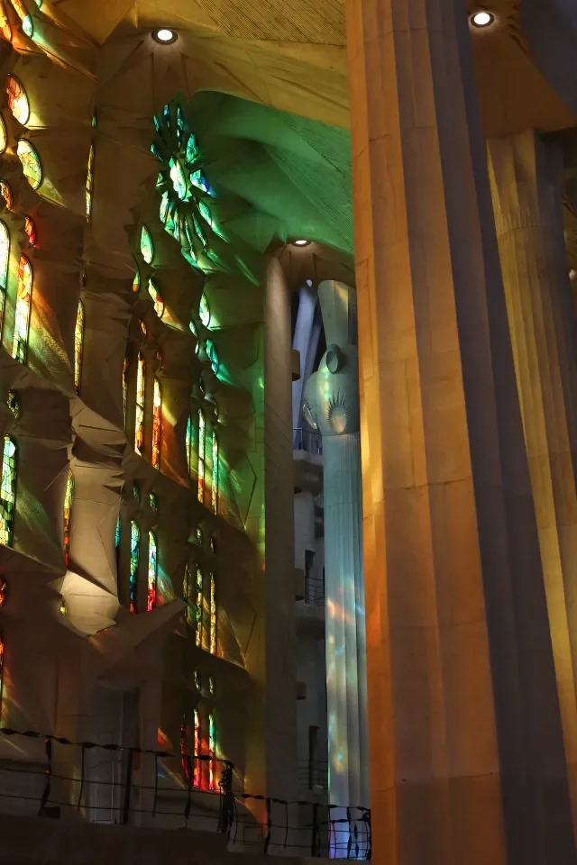 Barwne witraże i kolumny nawy Sagrada Família w Barcelonie z rzeźbą w tle