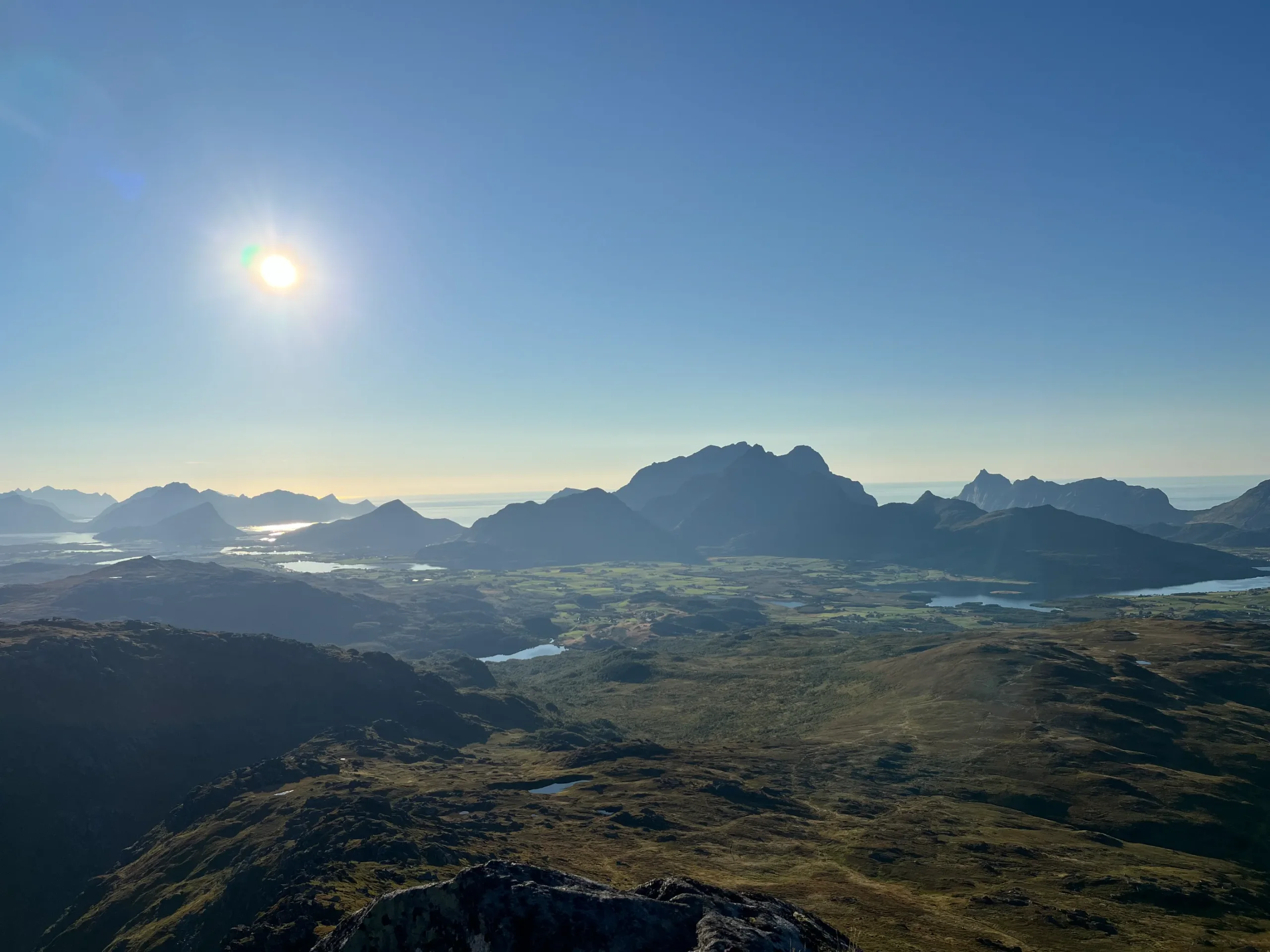 Rozlehlé panorama z vrcholu Blåtinden na ostrov Vestvågøya s mnoha jezery, fjordy a Norským mořem za slunečného dne