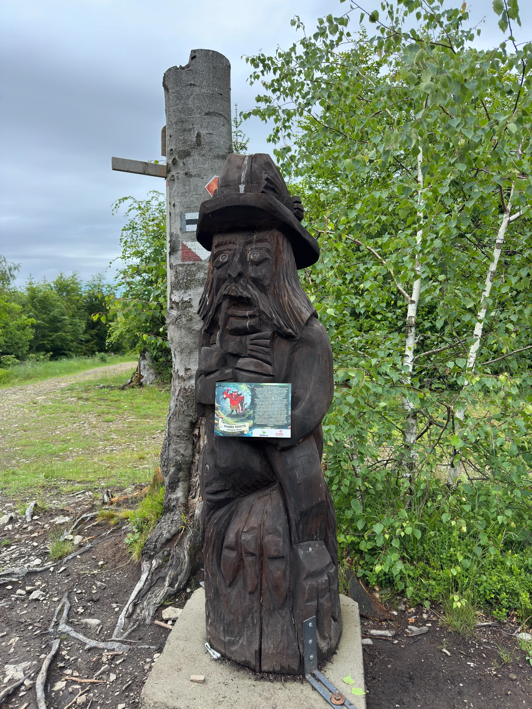 Carved wooden sculpture of Diabeł Rokita (devil from Beskid Śląski folklore) with an information board on the Utopiec Fairytale Trail in Brenna