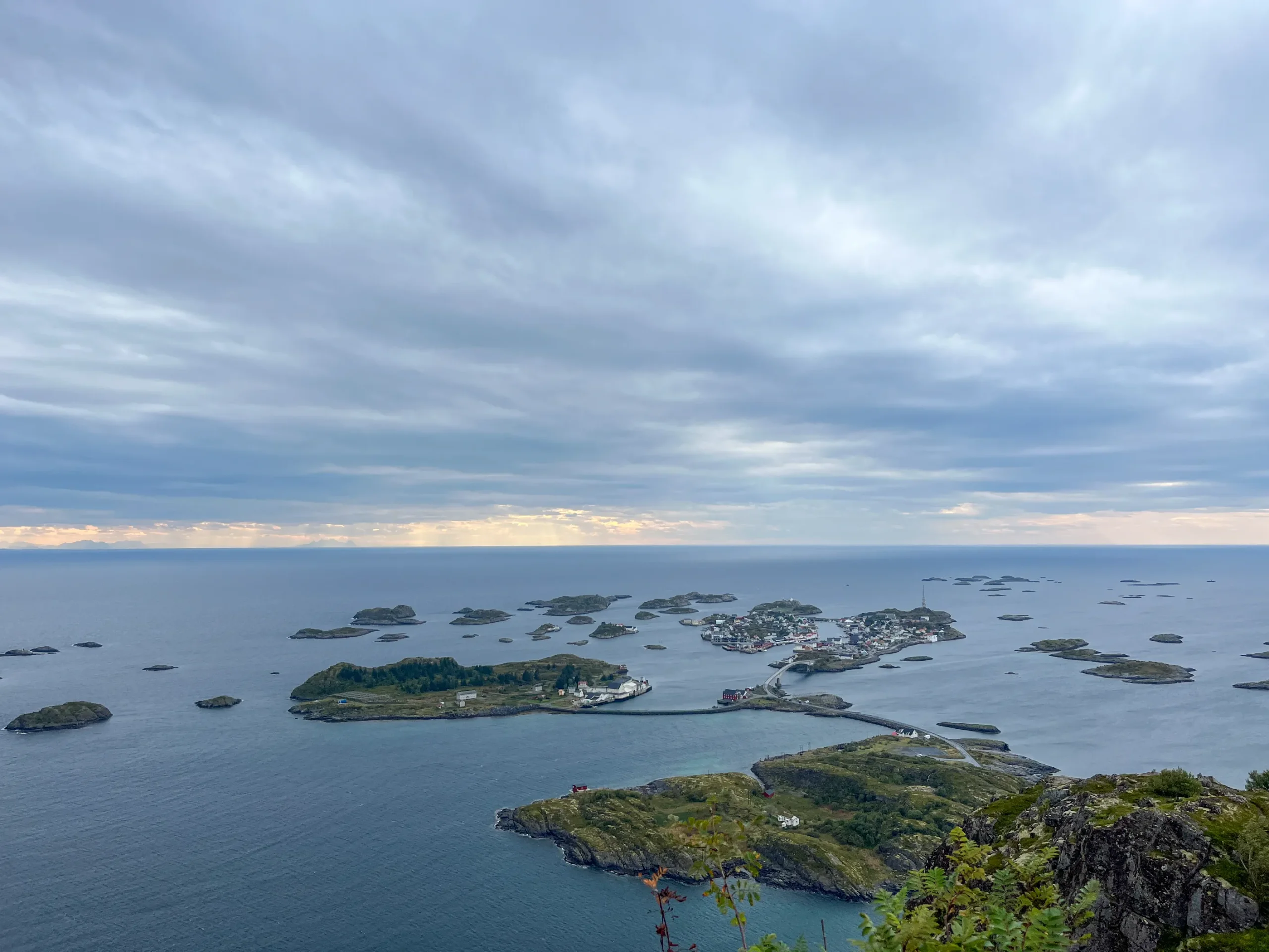 Široké panorama z vrcholu Nipen na Henningsvær s fotbalovým hřištěm a ostrovy souostroví táhnoucí se až za obzor