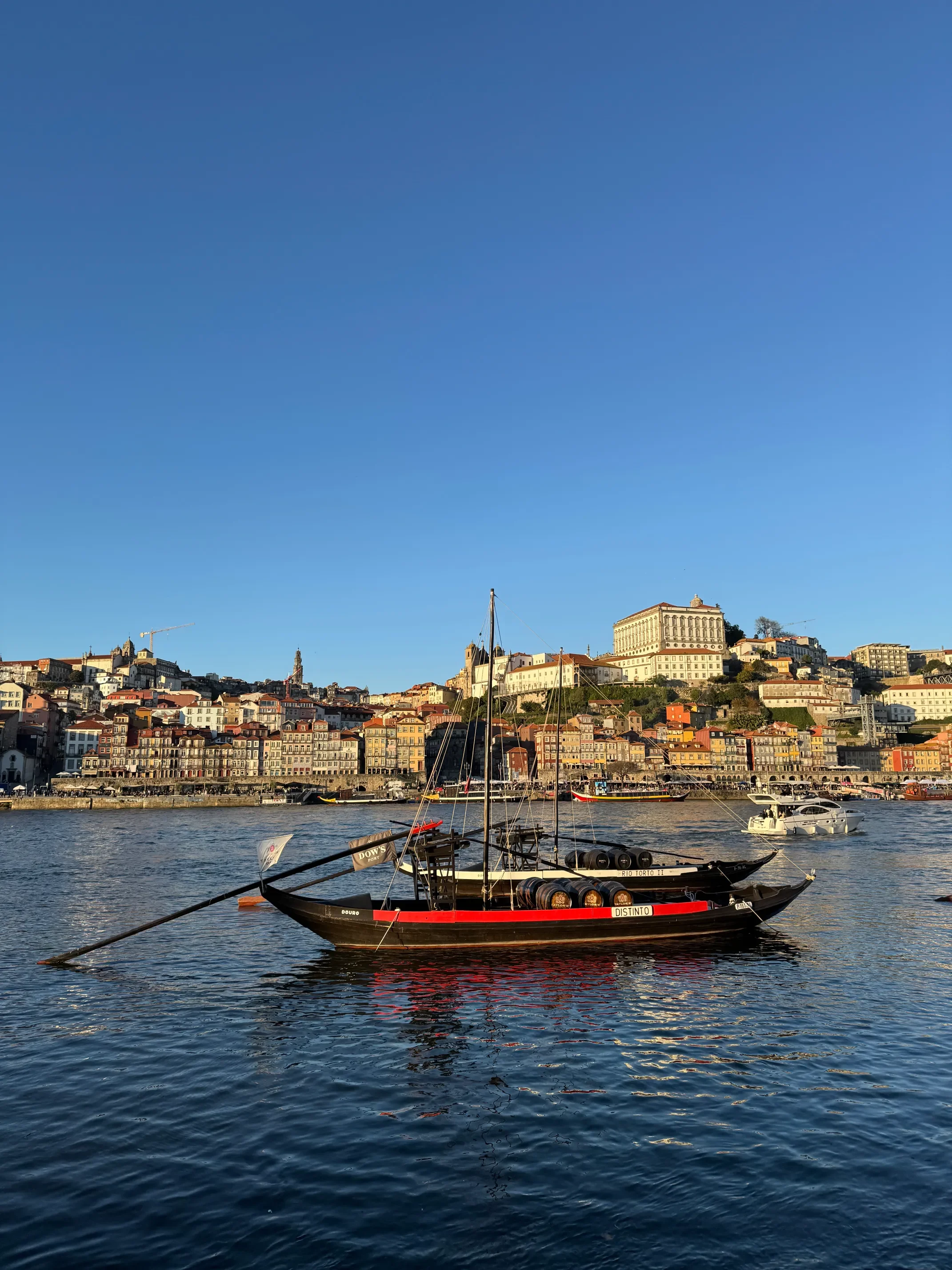 Tradycyjna łódź rabelo z beczkami wina na rzece Duero z panoramą Ribeira i centrum Porto w tle