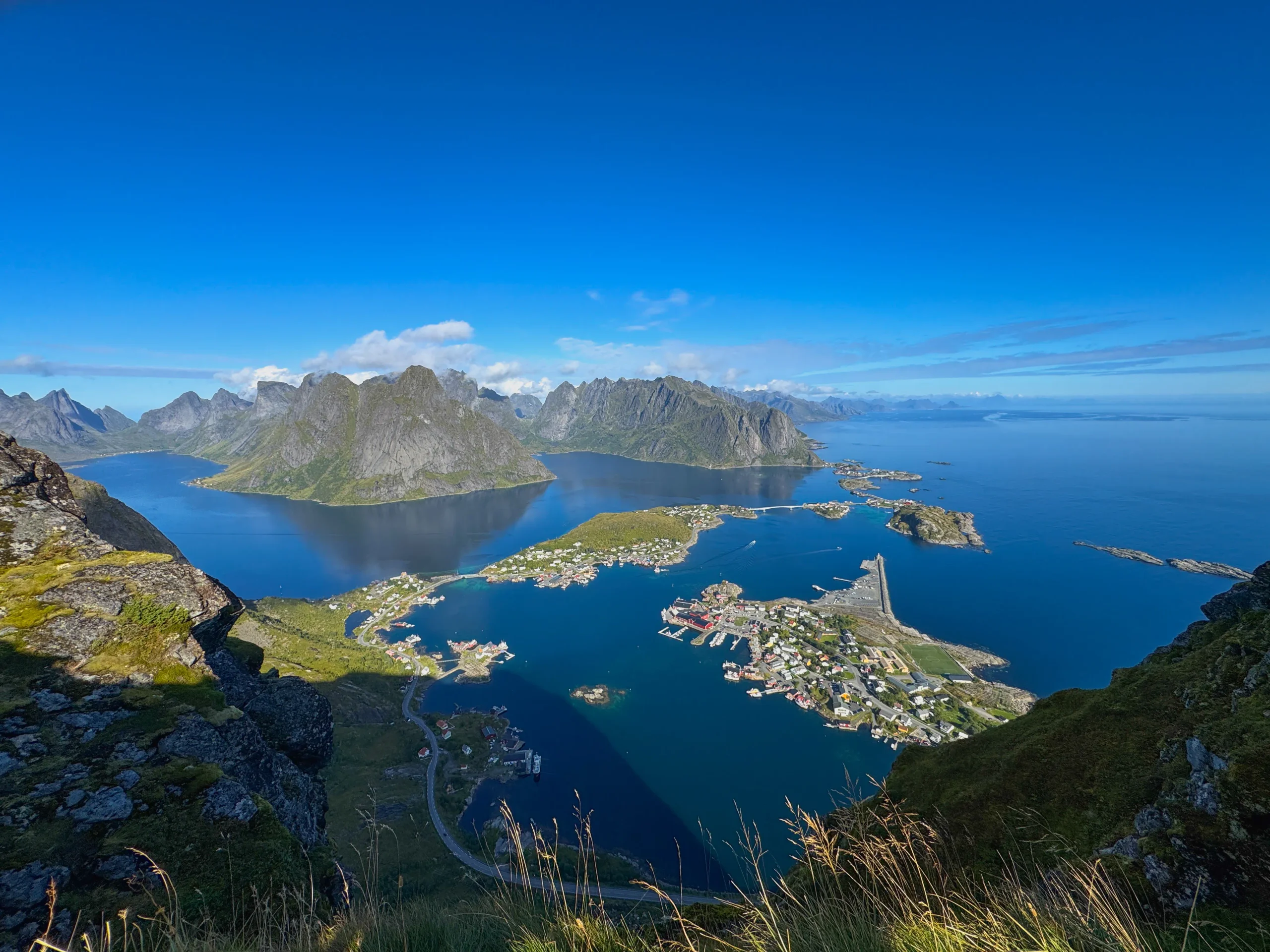 Pohlednicové panorama městečka Reine a ostrůvků na fjordu z vrcholu Reinebringen na Lofotech v létě
