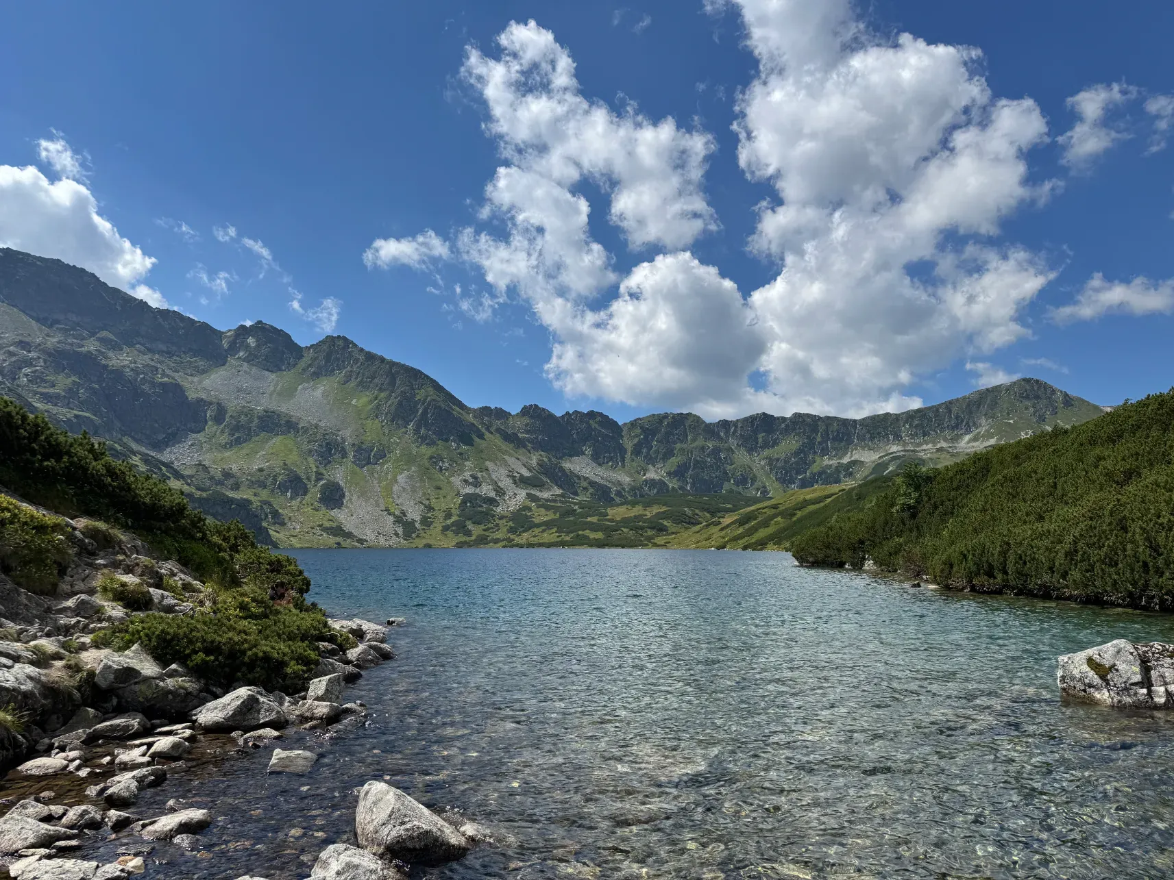 Crystal-clear alpine tarn in Dolina Pięciu Stawów valley surrounded by rocky High Tatra peaks in summer