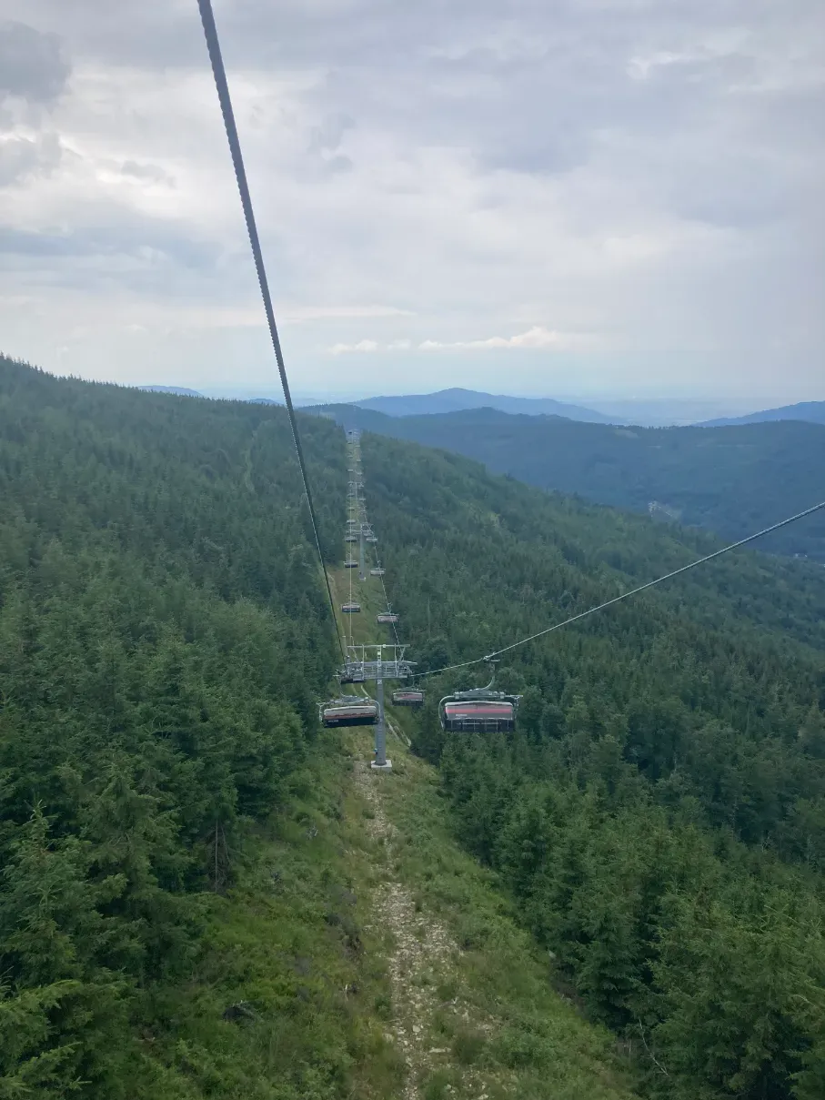 View from the Skrzyczne chairlift along the cable line over a forested slope in the Silesian Beskids