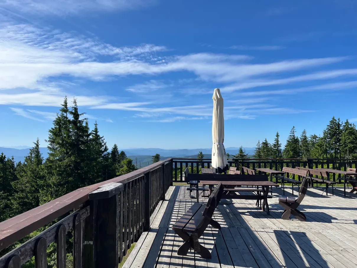 Outdoor terrace of the PTTK shelter on Skrzyczne summit with benches and Beskid mountain panorama