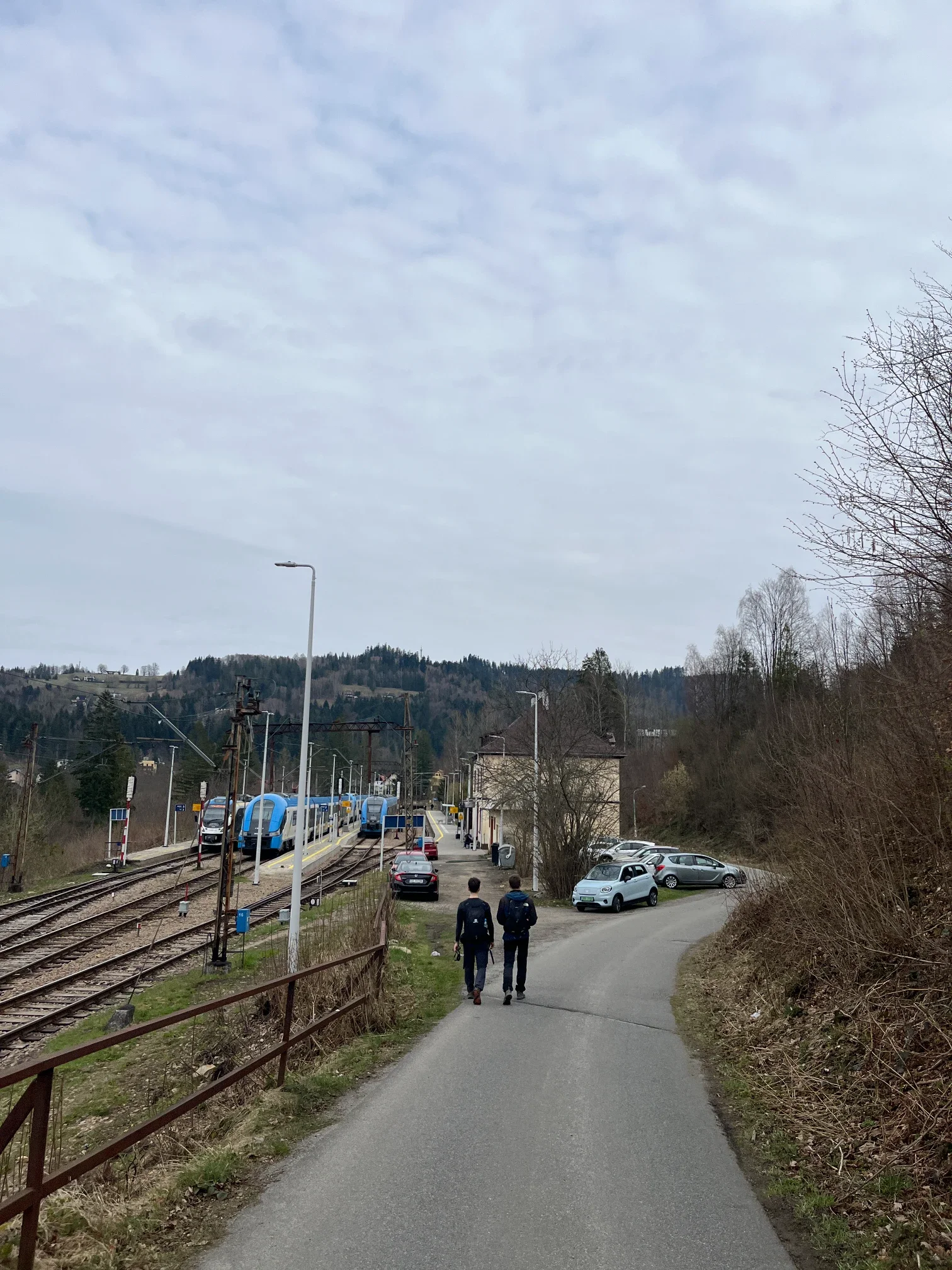 Dva turisté míří na trasu z parkoviště u železniční stanice Wisła Głębce na Velký Stožek na jaře