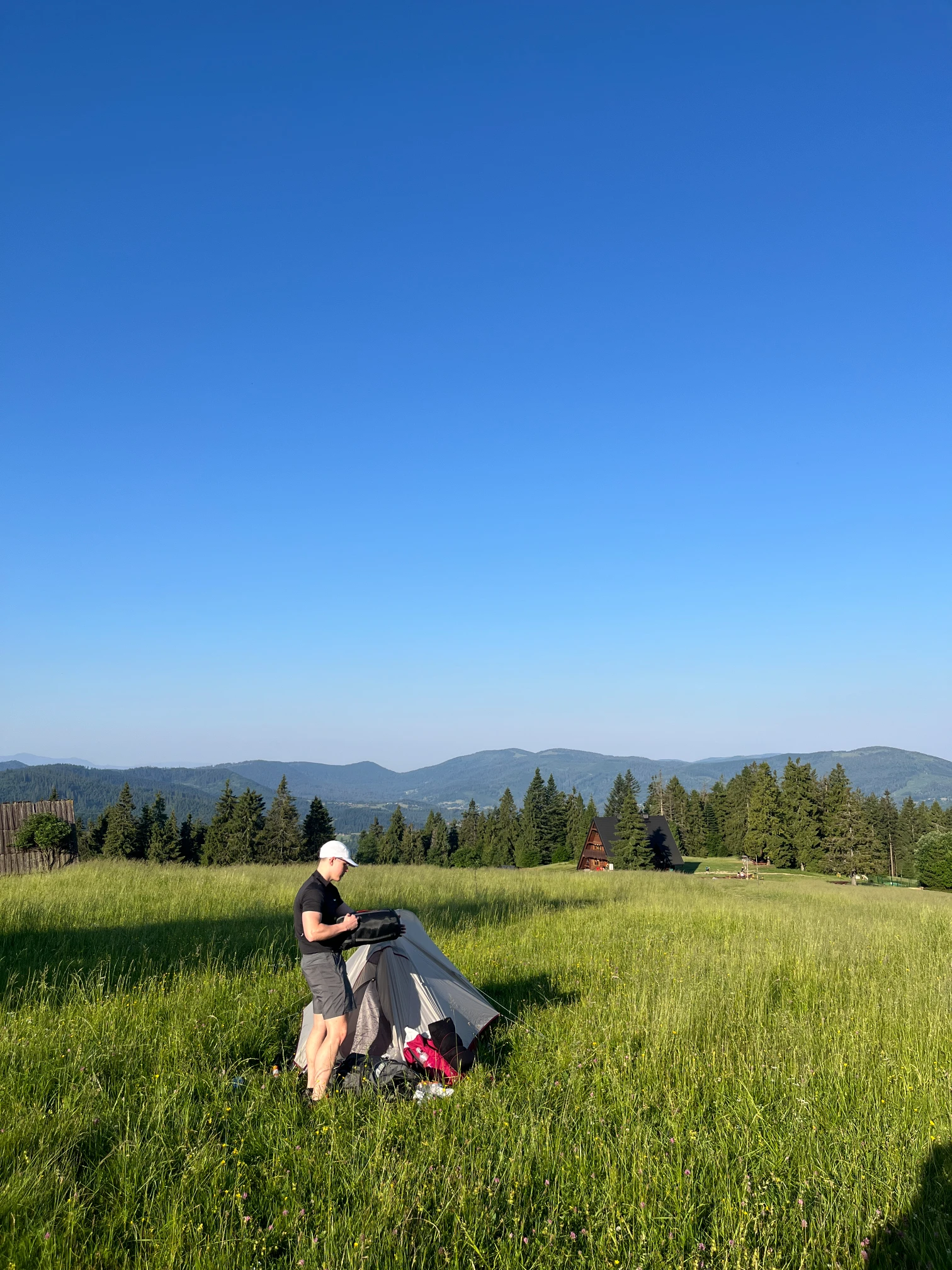 Packing up the tent in the morning on the meadow with a view of the Beskid peaks