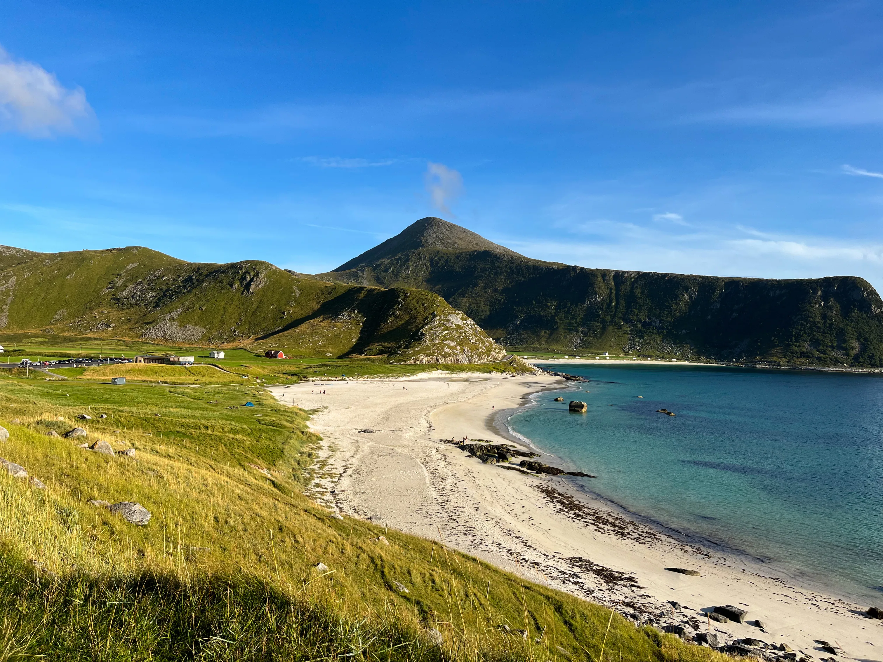 Biała piaszczysta plaża Haukland otoczona zielonymi górami