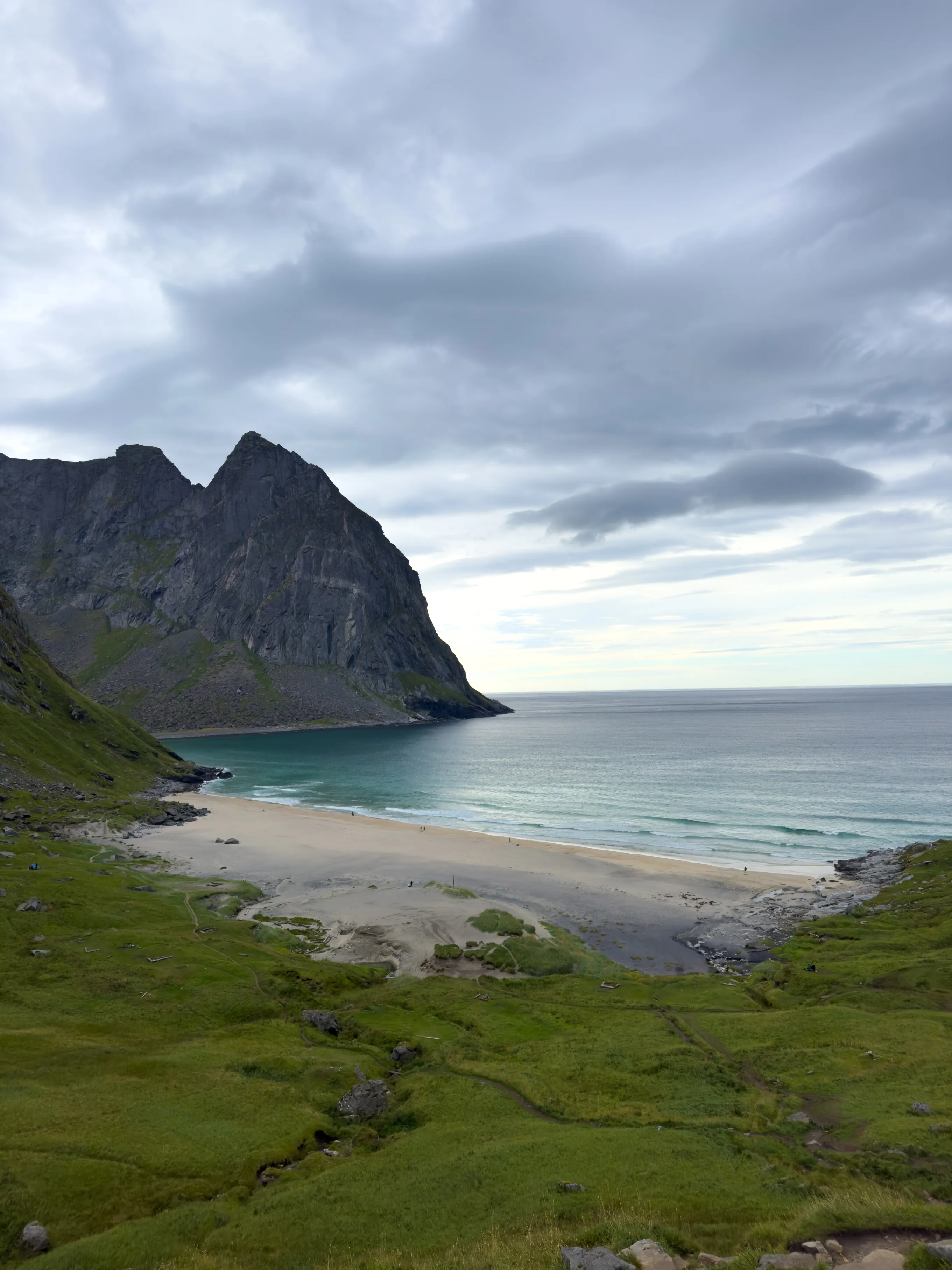 Dzika plaża Kvalvika z białym piaskiem i turkusową wodą otoczona klifami